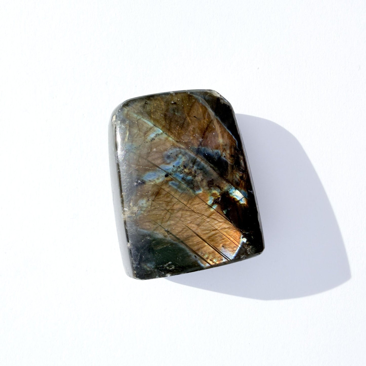 labradorite freeform crystal freeform with flash, on a white background with light shadow.
