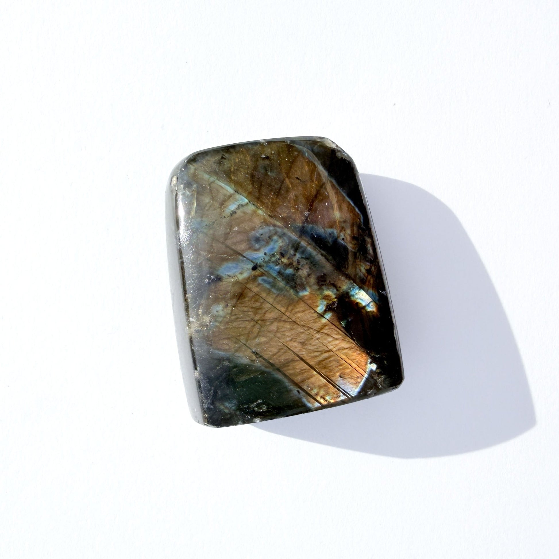 labradorite freeform crystal freeform with flash, on a white background with light shadow.